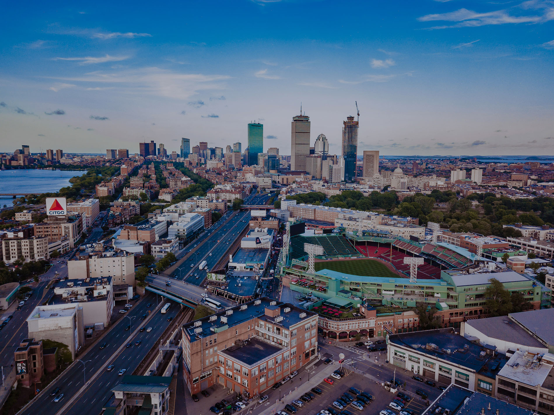 An aerial image of Boston, Massachusetts, showing the downtown skyline, Fenway Park, and the Charles River.