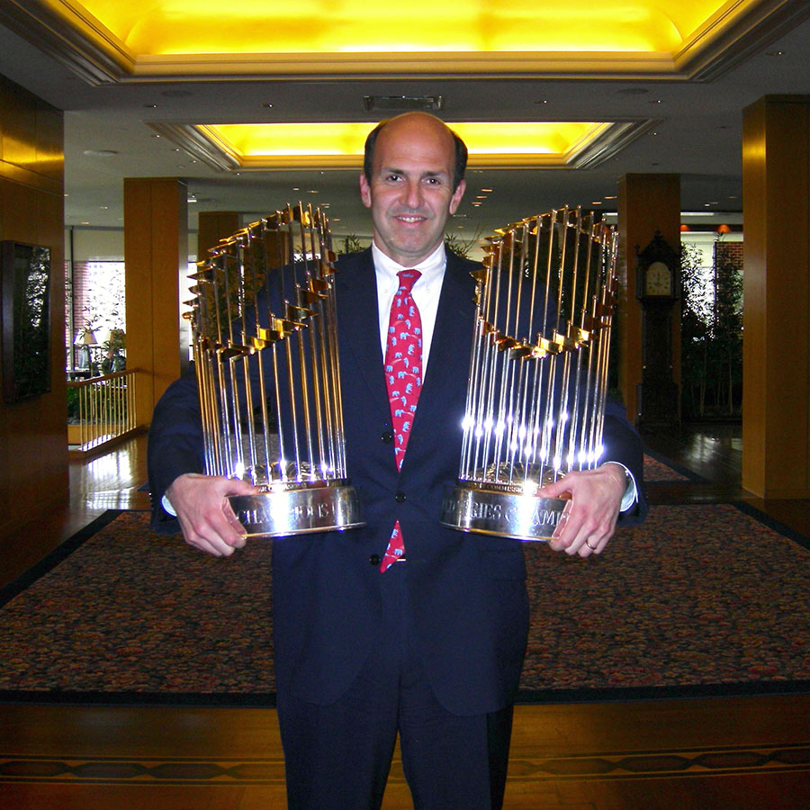 Dr. Thomas Gill holding two world series trophies in his arms.